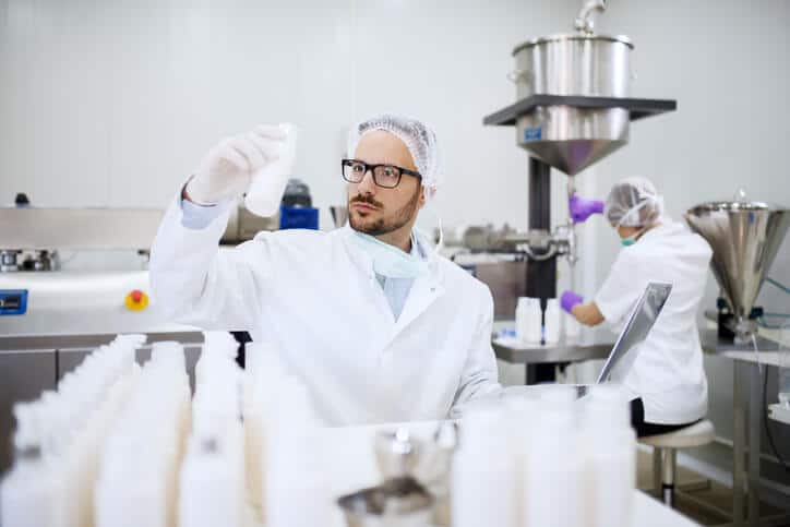 Regulatory affairs professional monitoring the quality of liquid white soap in a laboratory.