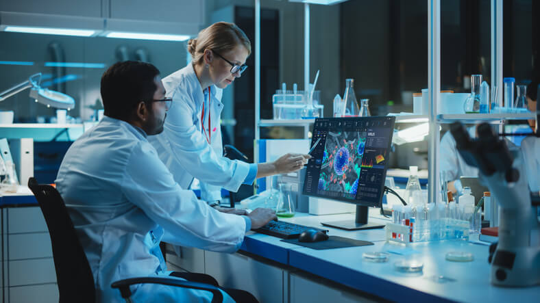 Two scientists working on a laptop during pharmaceutical research training