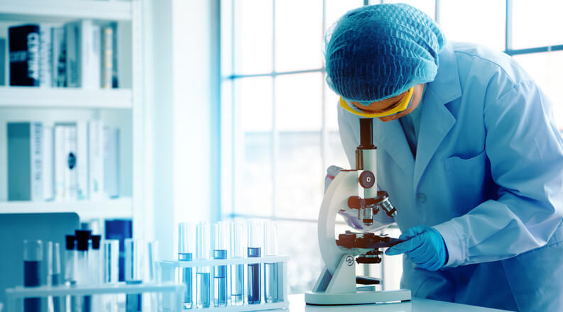 A scientist in a laboratory using a microscope during pharmaceutical research training