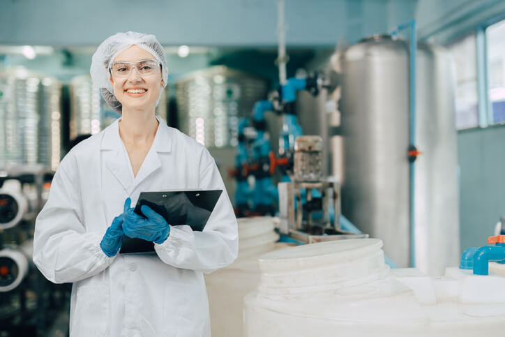 A smiling female product development technologist at a manufacturing facility after completing her food safety training.
