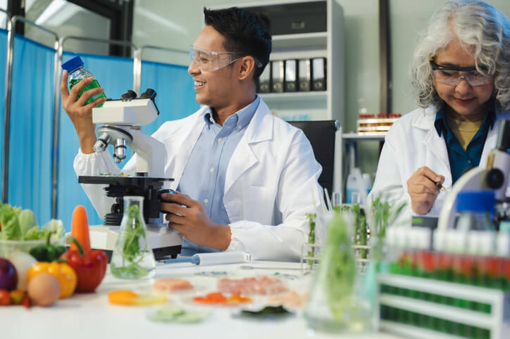 A male product development technologist interacting with a female colleague in a laboratory after completing his food safety training.