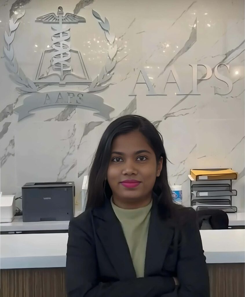 Prajakta standing in front of the AAPS logo during her clinical research training