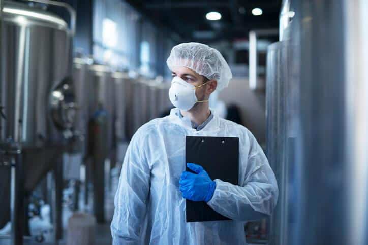 A food safety auditor evaluating equipment at a food processing plant after food safety training