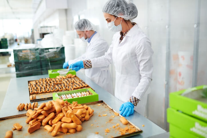 A team of production associates verifying the safety and quality of processed foods in a factory after their food safety training