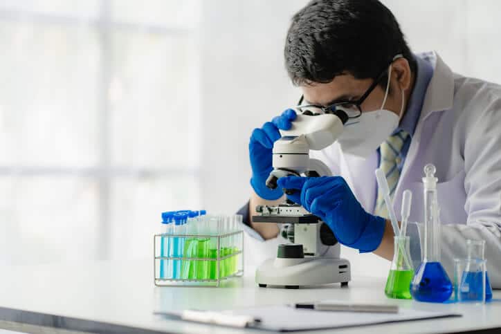 Male scientist looking into a microscope in a laboratory after pharmaceutical training