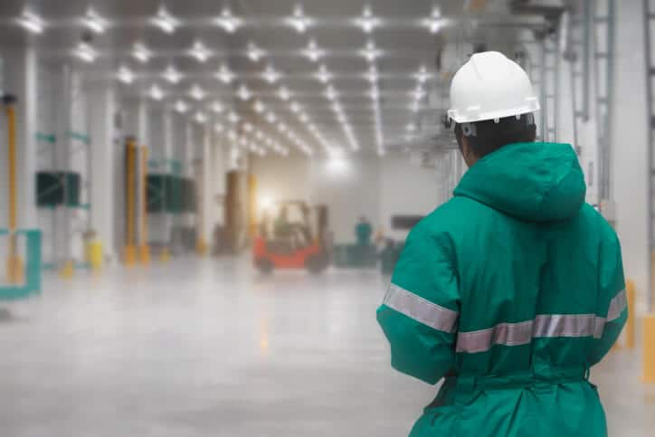 A QA professional supervising the unloading of pharmaceutical products in a freezing warehouse after completing his pharmaceutical training