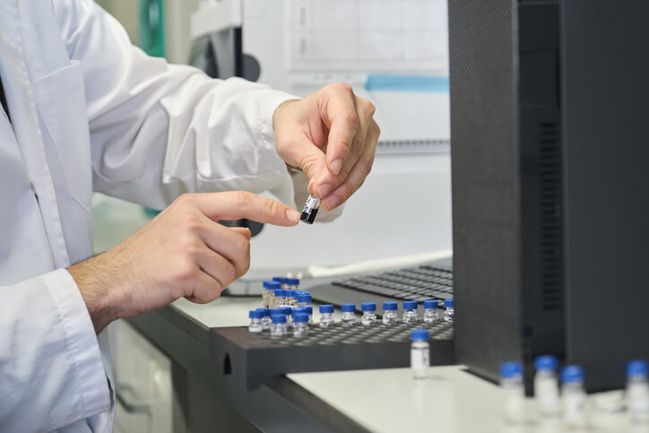 A scientist putting samples into the autosampler of the HPLC system after completing his pharmaceutical training