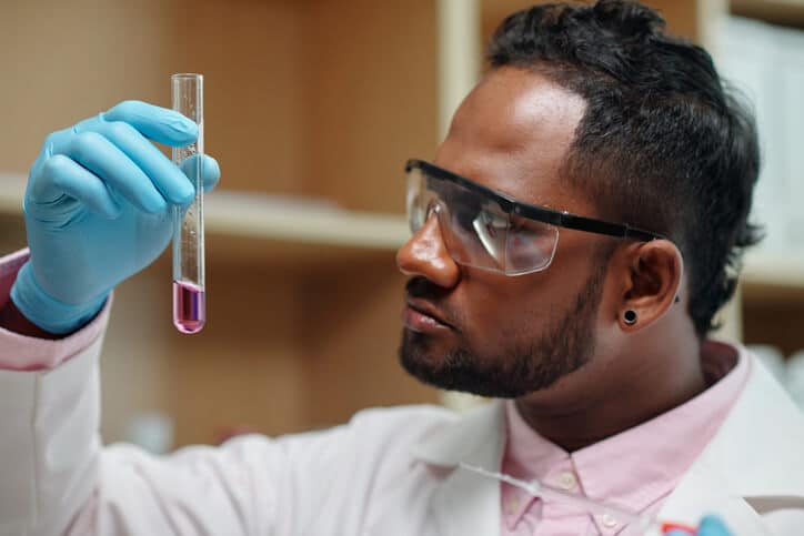 A male scientist looking at a sample in a test tube after completing his pharmaceutical training