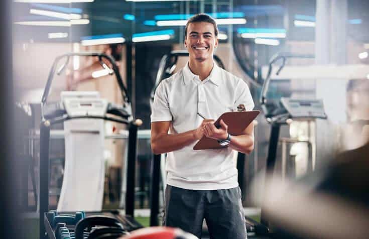 A smiling male health coach in a fitness centre after nutrition, health, and sports training.