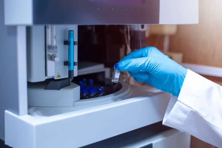 A female scientist moving the vial of sample out from the tray autosampler of the Liquid Chromatography Mass Spectrometer after her pharmaceutical training