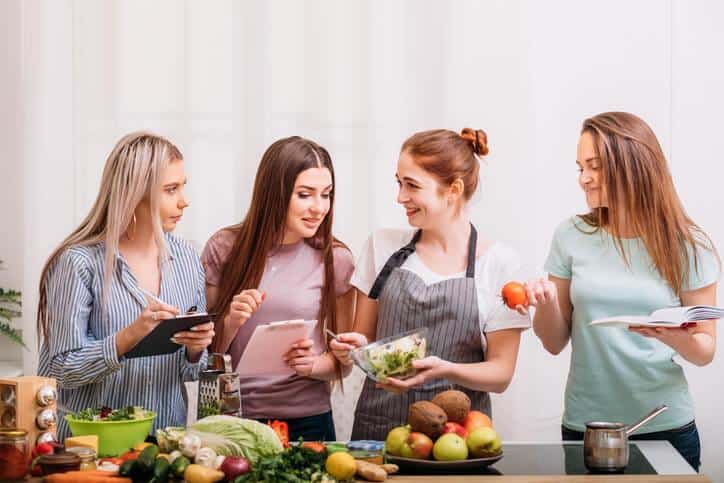 A smiling female nutrition educator interacting with three women after nutrition, health, and sports training.