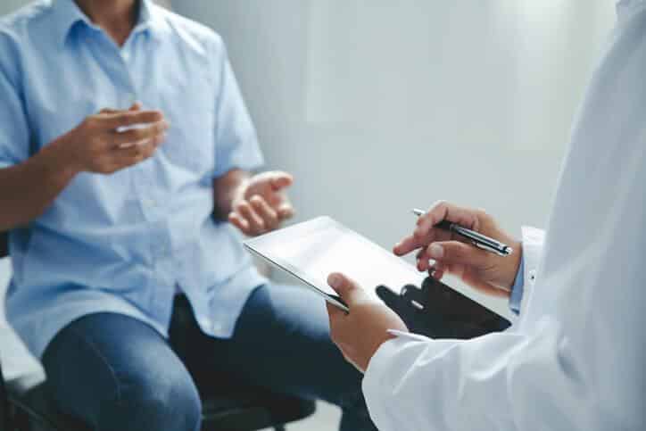 A pharmaceutical school graduate receiving information from a patient during a clinical trial.
