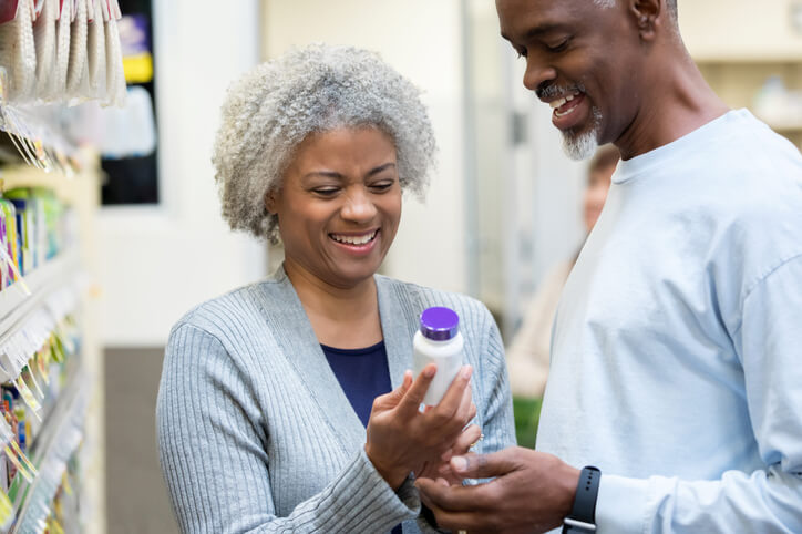 A clinical research training graduate reading bottle labels to a senior